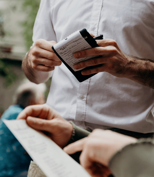 The inside of a restaurant a server taking and order from a customer who is holding a menu